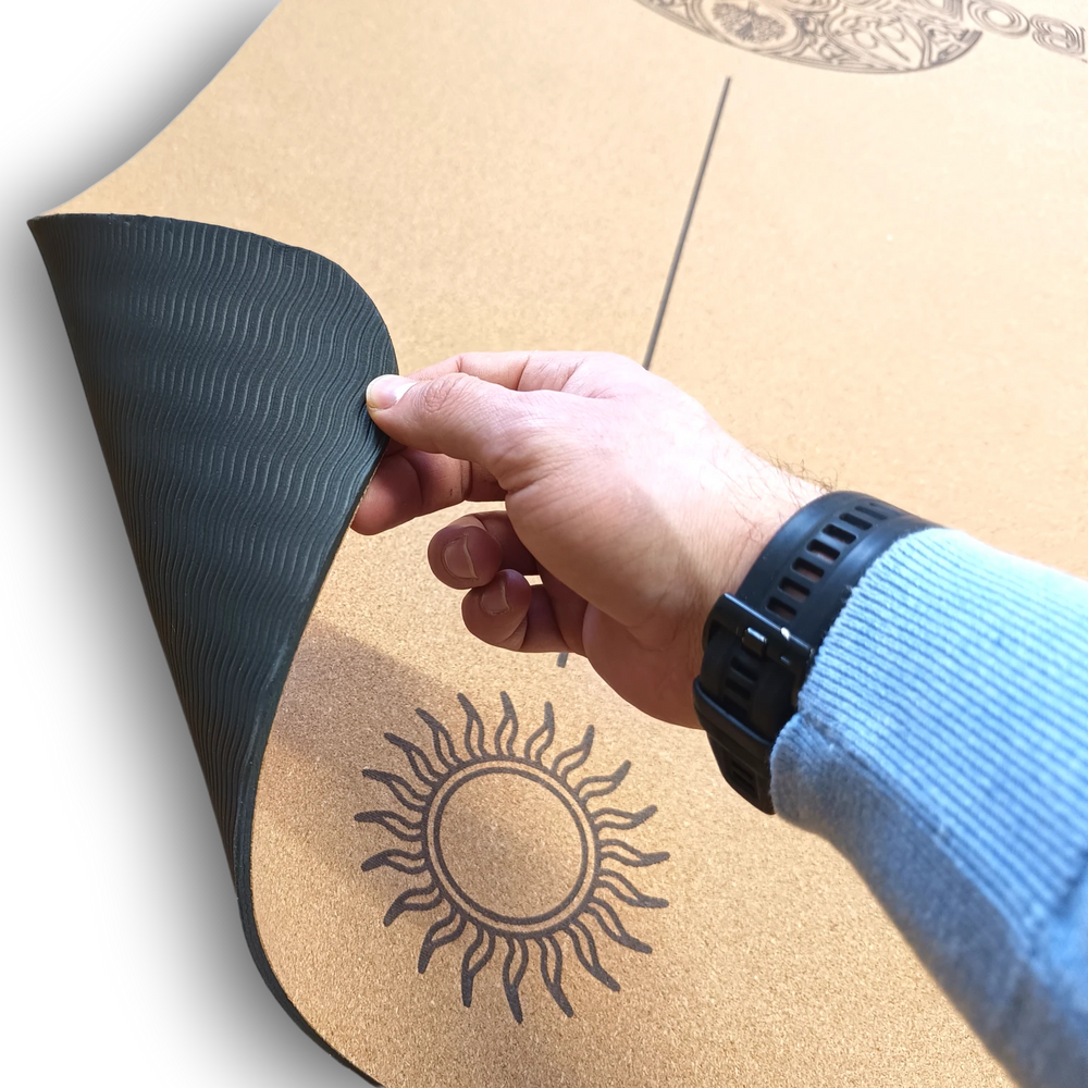 Hand holding a black tpe yoga cork mat