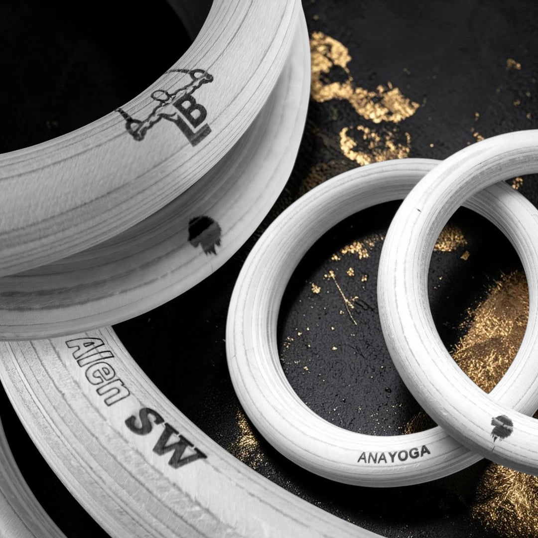 Gymnastic rings with branding on a dark surface with gold accents