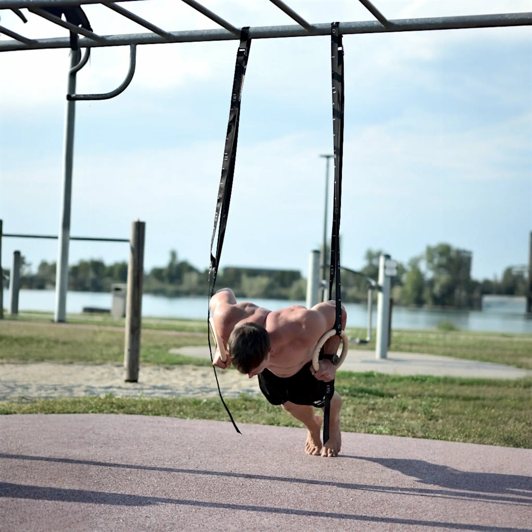 Person performing a push-up on workout rings outdoor.